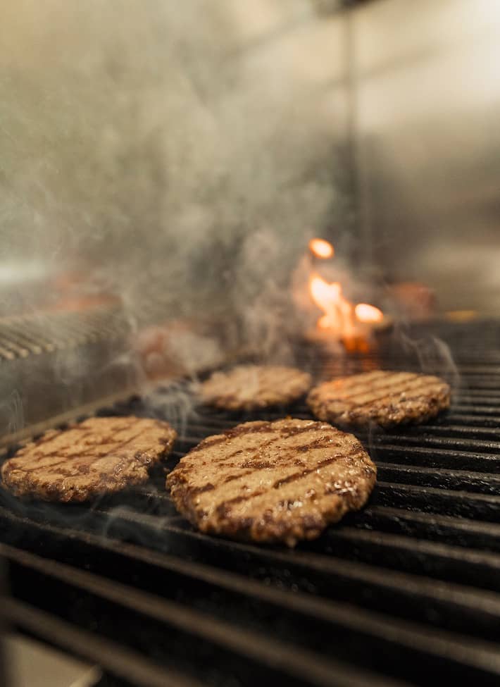 Flame-grilled patties on the grill at Louis Burger